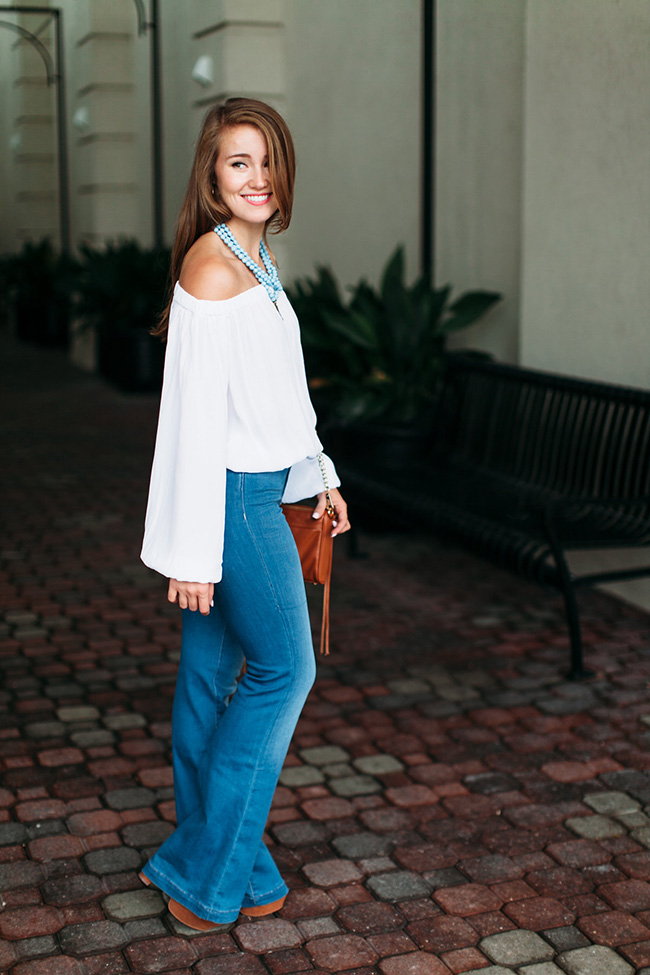 bell bottom jeans, tassel crossbody, off the shoulder long sleeved top, akola project collar, seventies style, southern girl style, lace up platforms